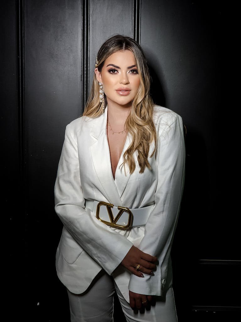Stylish portrait of a woman in a white blazer with glamorous accessories.